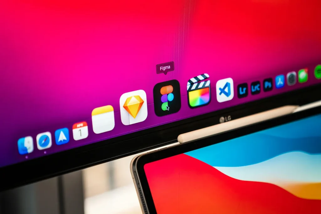 A monitor showing the Figma app icon beside a laptop.