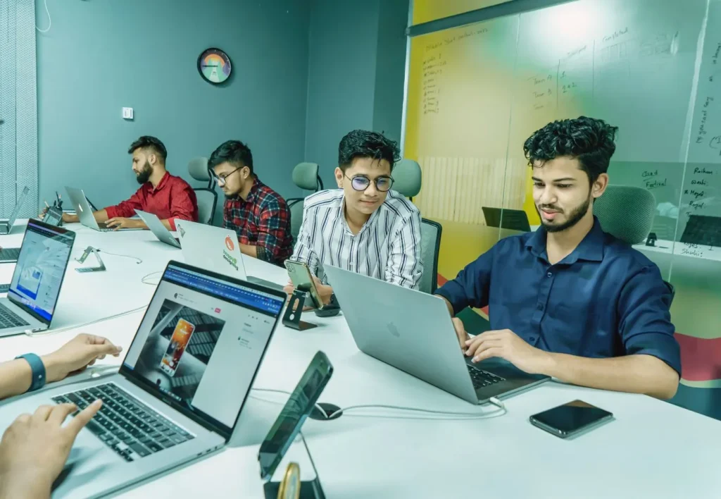 Professionals using laptops together in an illustrative digital workspace.