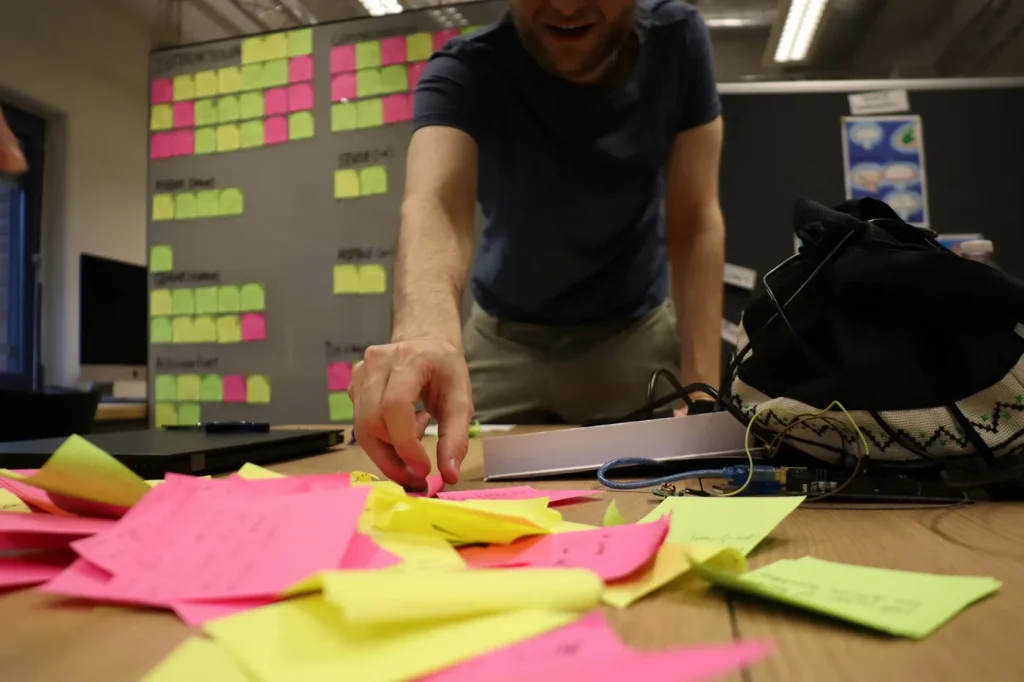 A person organizing sticky notes in front of an affinity diagram.